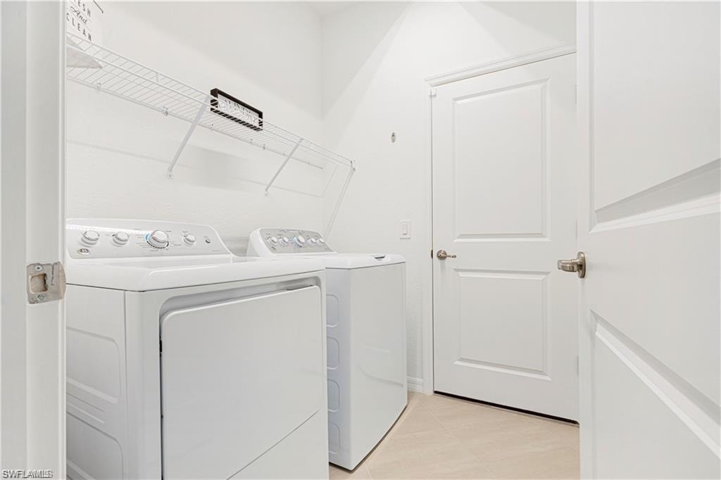 Dedicated laundry area featuring white walls, wire shelving, and a light-toned tile floor