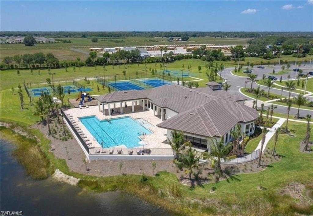 Community clubhouse featuring an expansive swimming pool, multiple tennis courts, and a playground