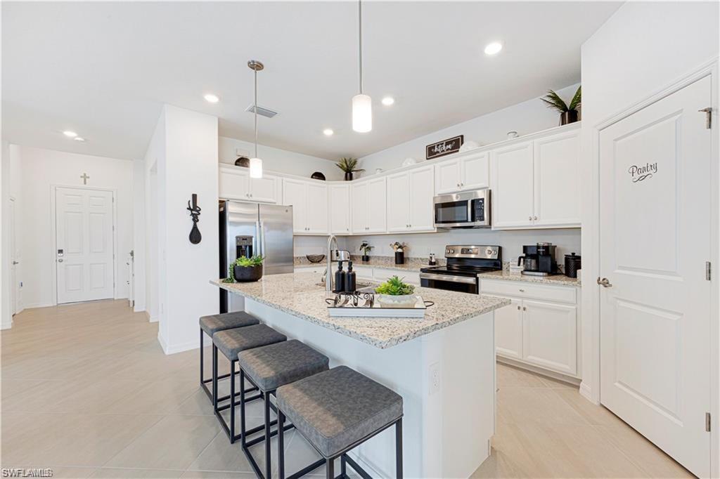 Modern kitchen featuring white cabinetry, stainless steel appliances, and a central island with a granite-finish countertop