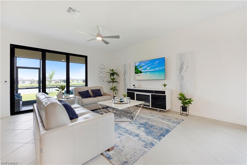Spacious living area featuring large sliding glass doors, a ceiling fan, and light-toned tile flooring