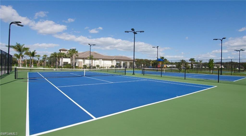 Multiple hard-surface tennis courts featuring blue playing areas and green surrounds