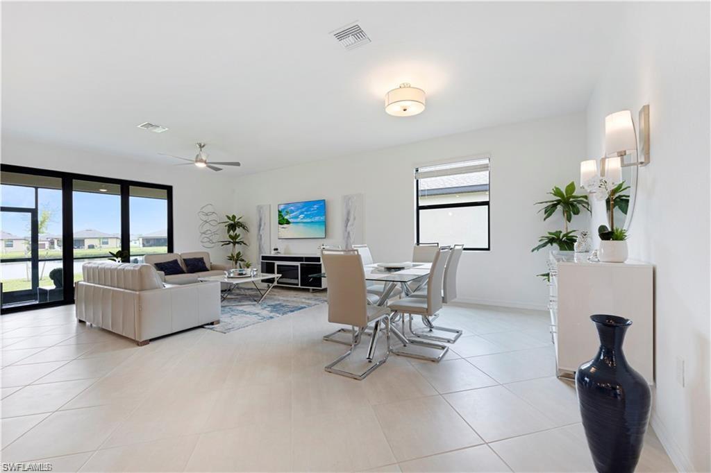 Open-concept living area featuring light-toned tile flooring, recessed lighting, and a ceiling fan