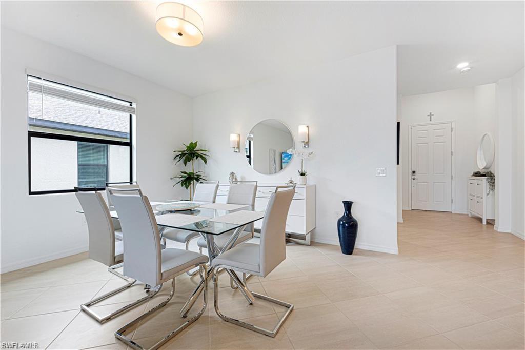 Bright dining area featuring light-toned tile flooring, a large window with blinds, and recessed lighting