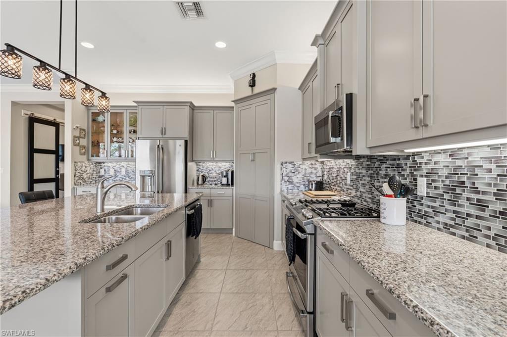 Elegant kitchen accents, stainless steel appliances, glass tile backsplash.