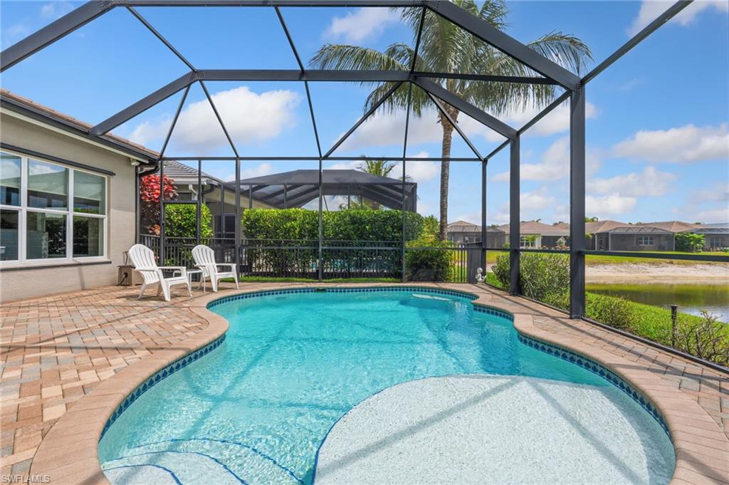 Sparkling heated pool with sunshelf, screened cage and view of lake.