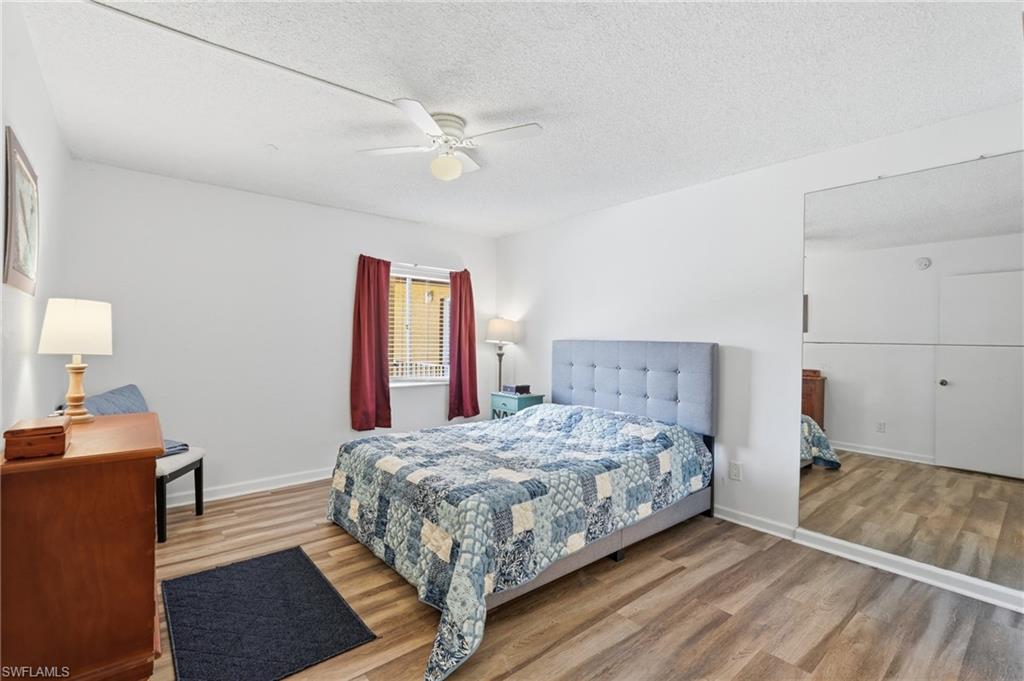 Primary bedroom featuring wood-finish flooring, a window with horizontal blinds, and a ceiling fan