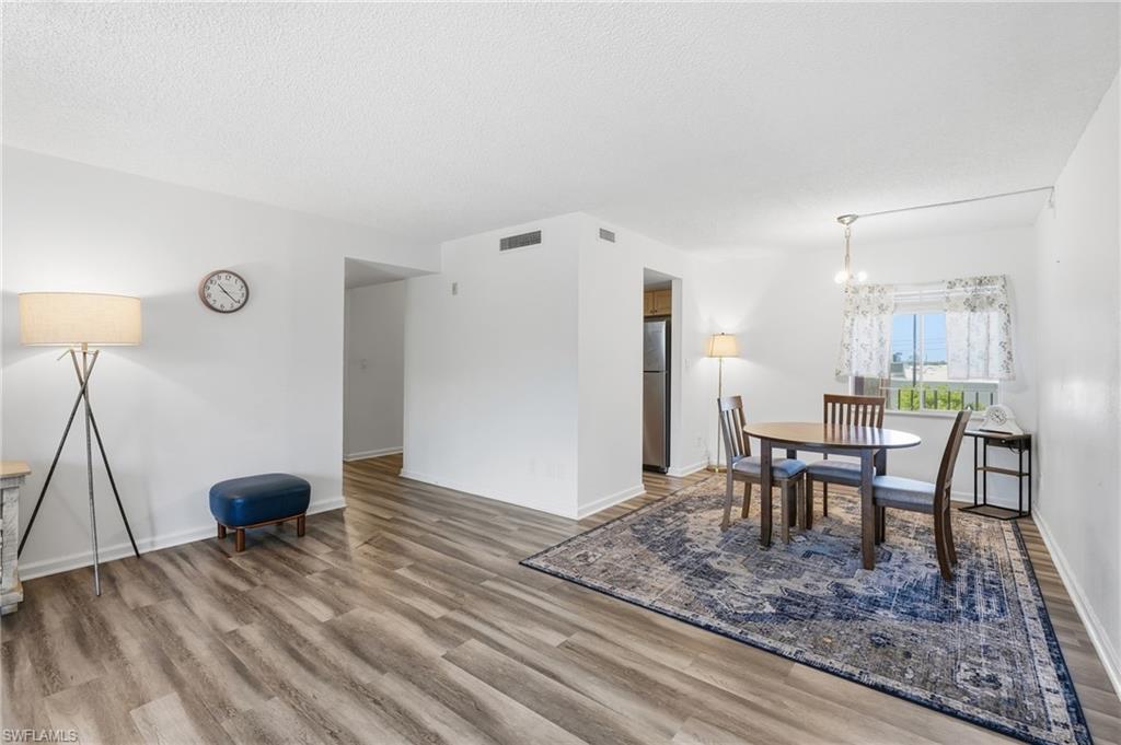 Open-concept living space featuring wood-finish flooring throughout, white painted walls, and a dropped ceiling