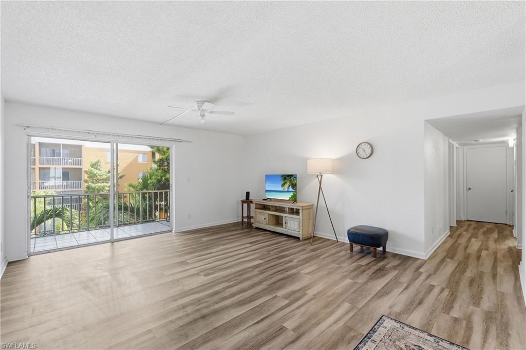 Spacious living area featuring wood-finish flooring and a ceiling fan