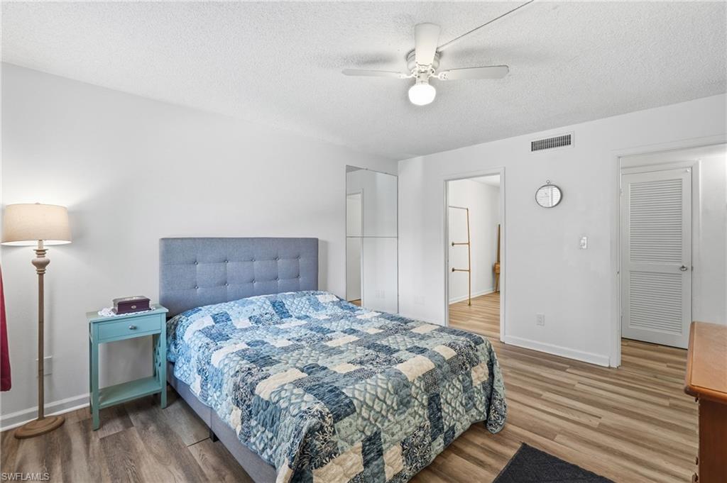 Bedroom featuring light wood-finish flooring, white painted walls, and a ceiling fan with integrated lighting