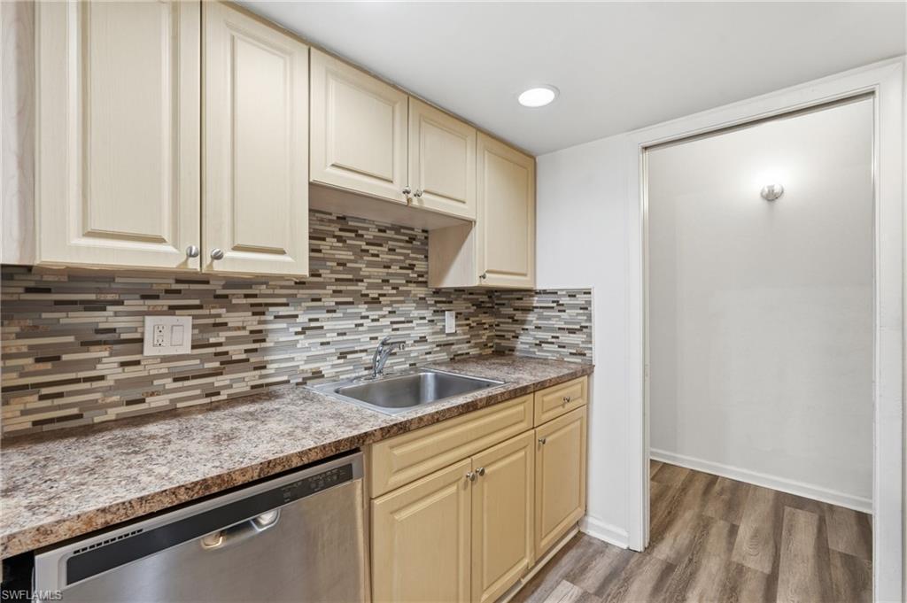 Kitchen featuring light wood-finish cabinetry, a stainless steel sink, and a multi-tone mosaic tile backsplash