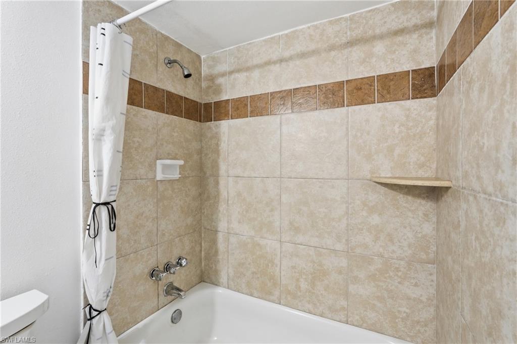 Bathtub with tiled surround featuring a decorative accent band