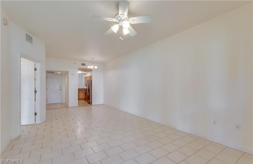 Spacious room featuring light-toned tile flooring, ceiling fan with integrated lighting, and neutral wall tones
