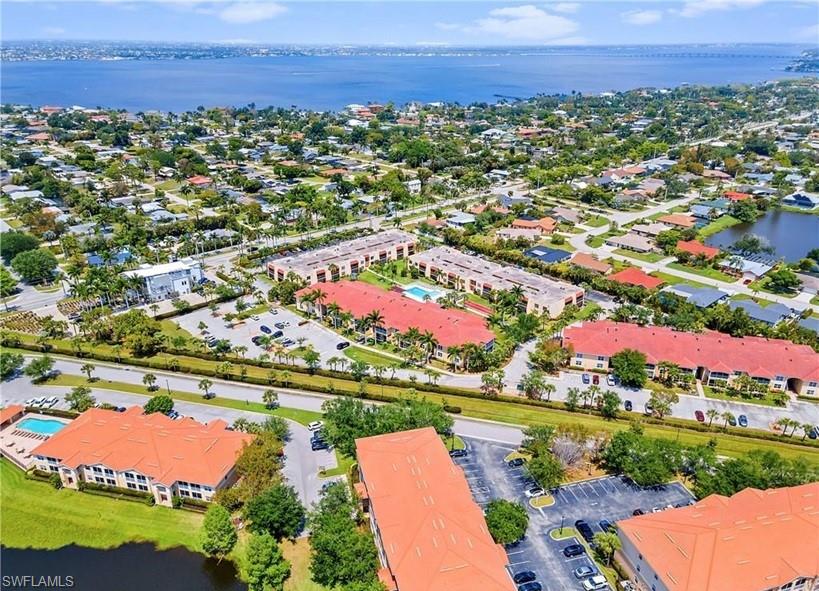 Aerial perspective showcasing multiple residential buildings with terracotta-style roofs, surrounded by lush green landscaping and mature palm trees