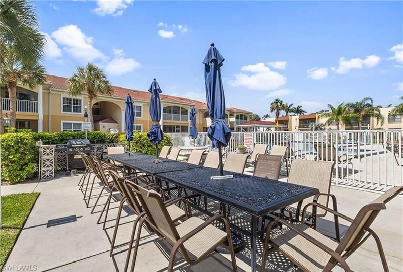 Outdoor dining area with multiple tables, umbrellas, and chairs, featuring a built-in grill station