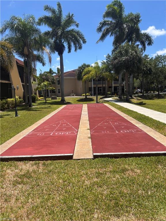 Outdoor recreation area featuring two shuffleboard courts with red playing surfaces, surrounded by manicured grass lawns
