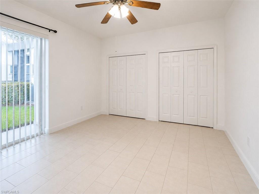 Spacious room featuring light-toned tile flooring, white walls, and a ceiling fan with integrated lighting