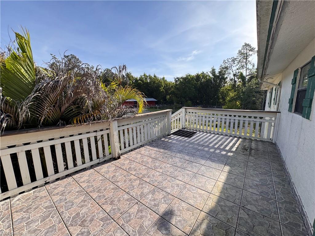 Outdoor patio featuring patterned tile flooring, white wooden railing, and a textured exterior wall