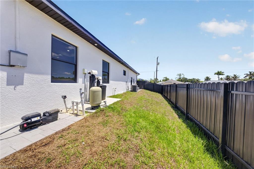 Exterior side of the property featuring a white stucco finish, dark-framed windows, and a black metal privacy fence