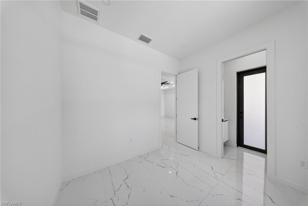 Bright room featuring white walls, white ceiling, white doors, and white marble-look flooring