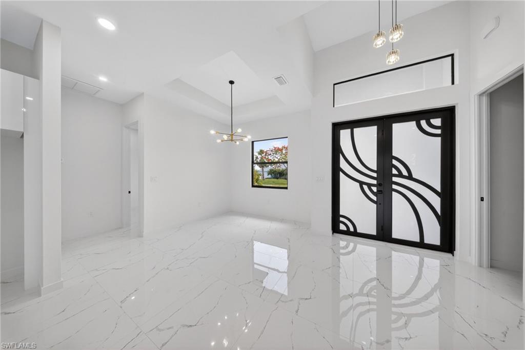Entryway featuring double doors with decorative frosted glass, an overhead transom window, and a vaulted ceiling