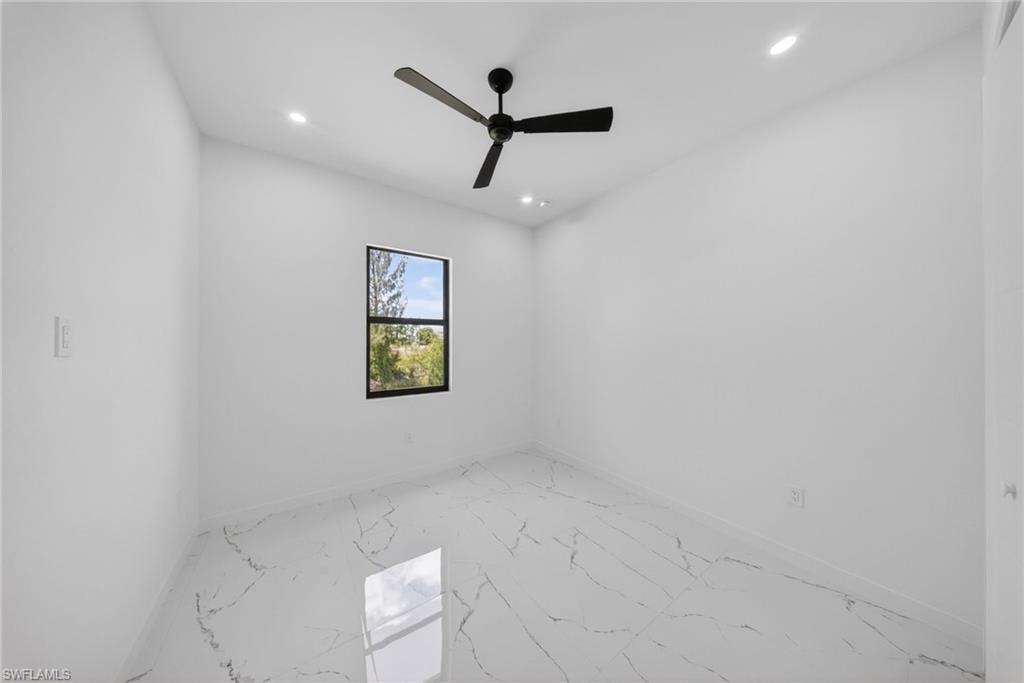 Room featuring large-format tile flooring with a marble-effect pattern, a single black-framed window, and a black ceiling fan