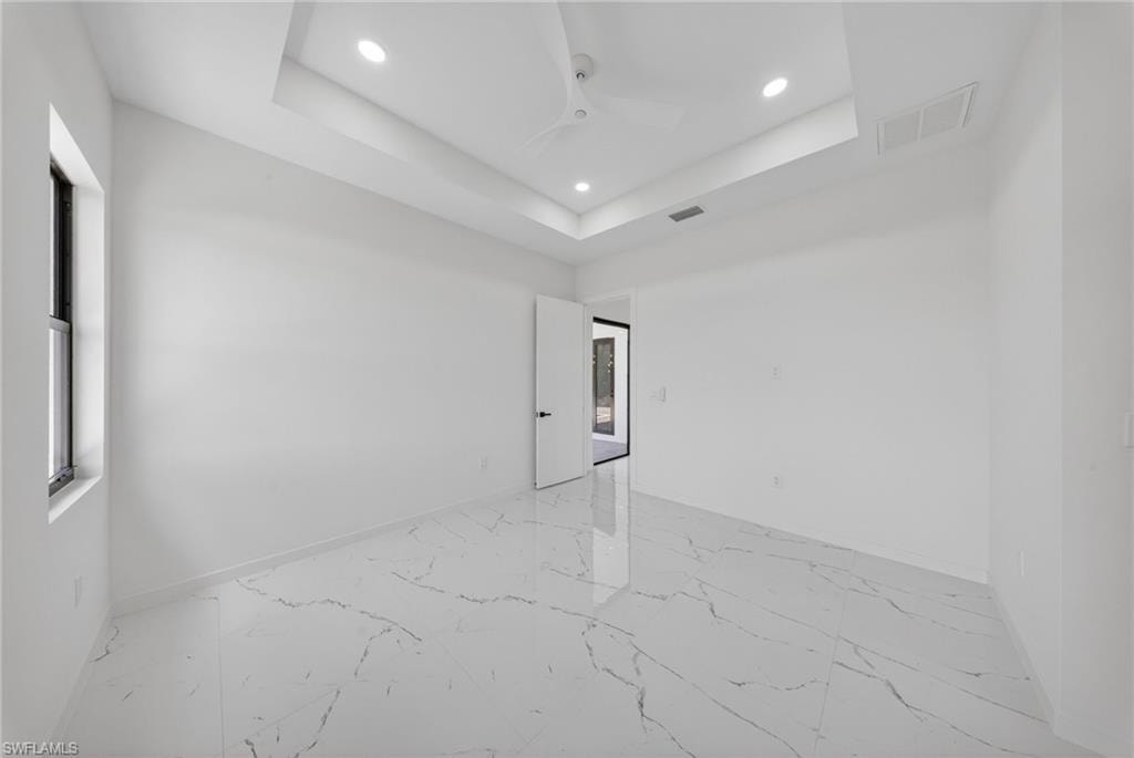 Spacious room featuring white walls and large-format porcelain tile flooring with grey veining