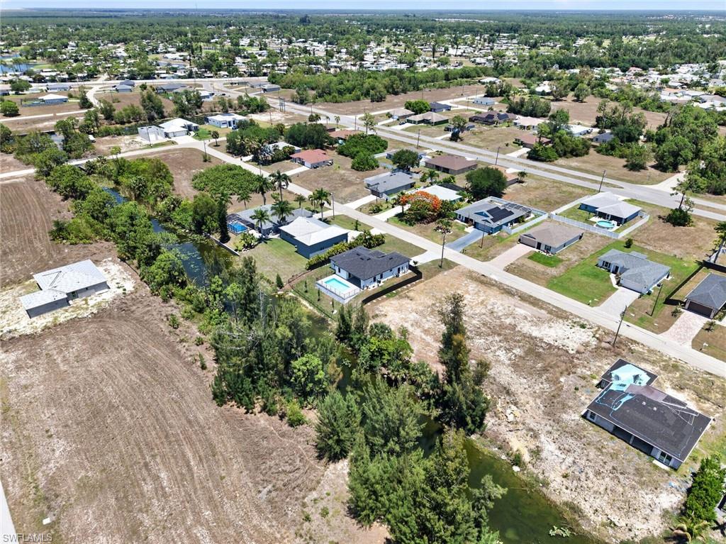 Expansive aerial view of a residential area featuring numerous single-story homes, a network of paved roads, and several properties with private swimming pools