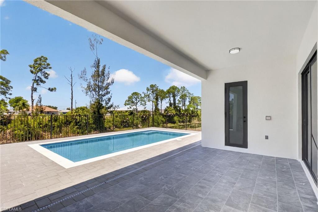 Covered patio with large format gray tile flooring and a rectangular swimming pool featuring a white coping edge