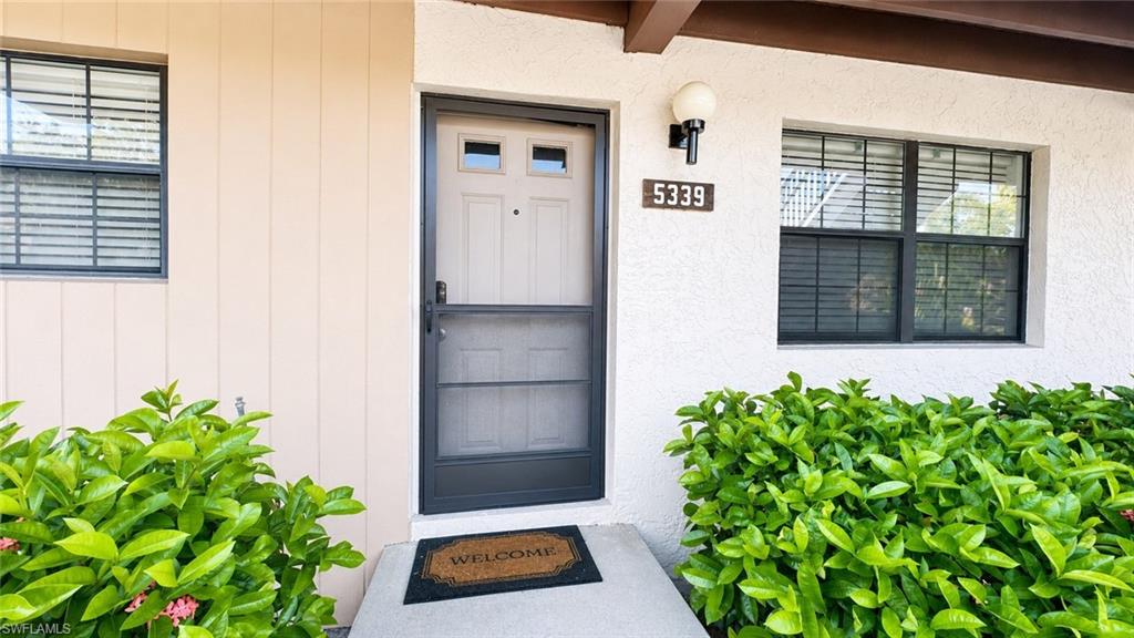 Entryway featuring a paneled door with small window accents, a dark screen door, and a wall-mounted light fixture