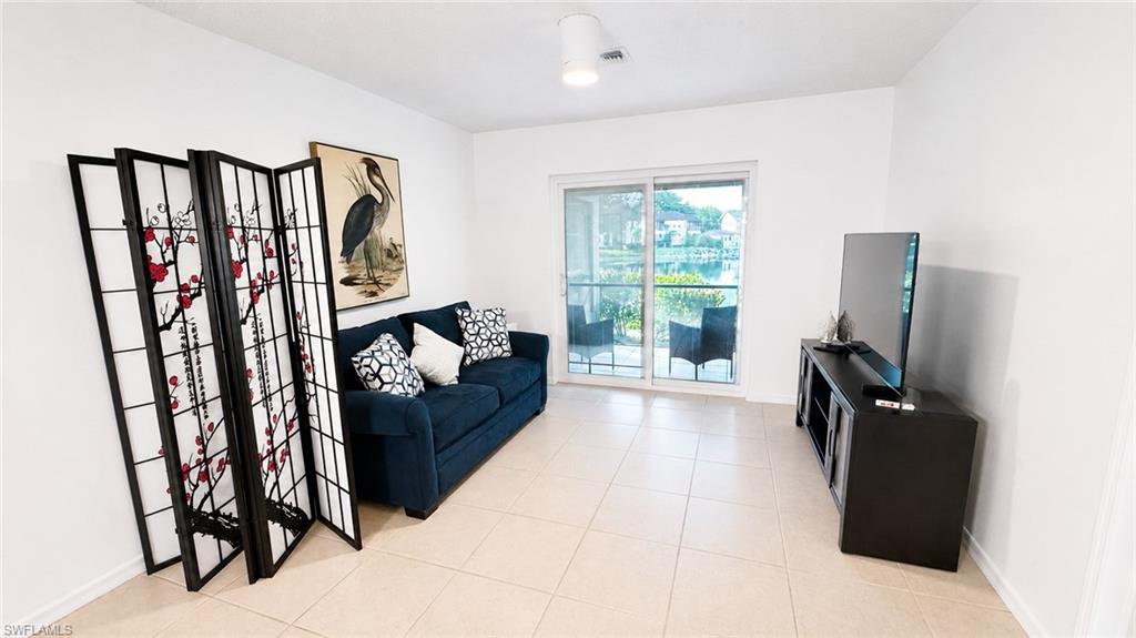 Living area featuring neutral tile flooring, white walls, and a ceiling fan