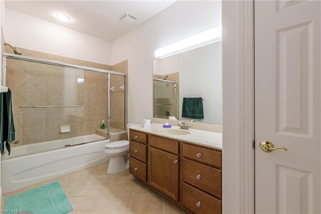 Full bathroom with toilet, vanity, shower / bath combination with glass door, and tile patterned flooring
