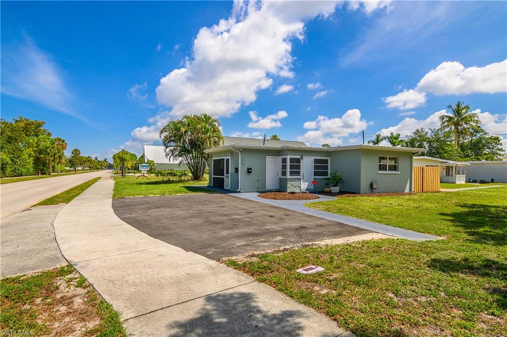 Corner-lot Naples residence featuring a private driveway, expansive yard space, and convenient access to downtown Naples amenities.