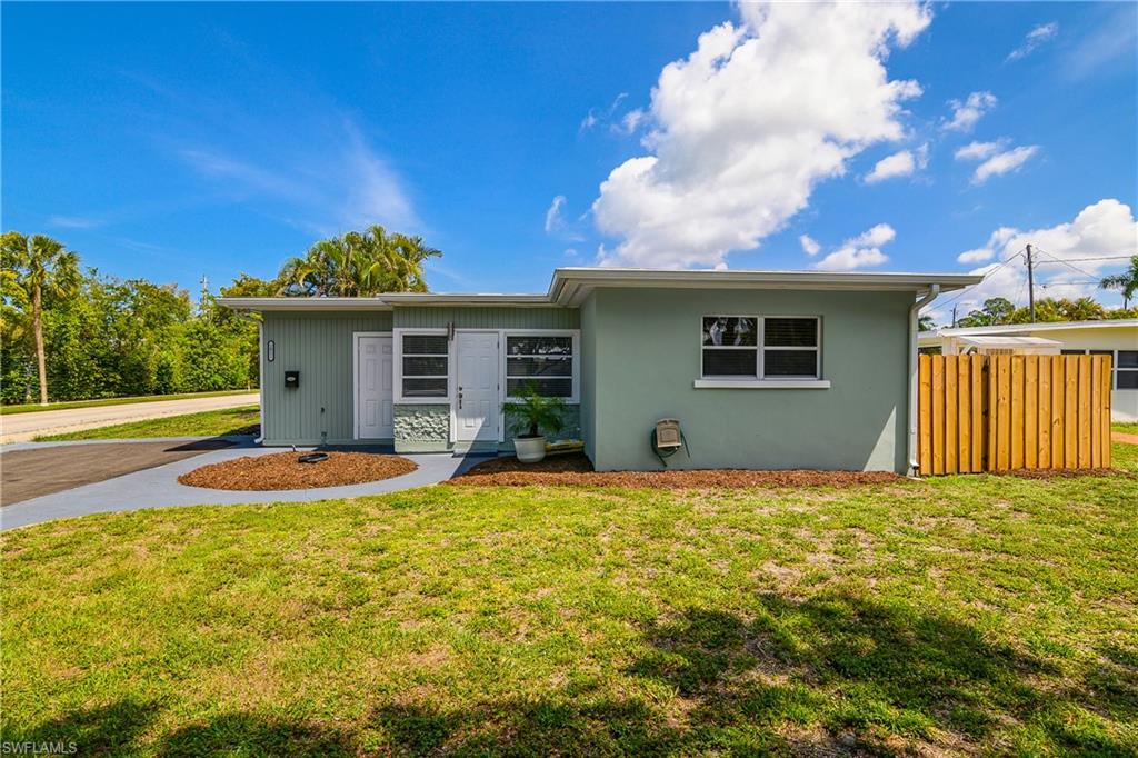 Front exterior of this Naples Florida home featuring a private entrance, driveway parking, and a spacious yard.