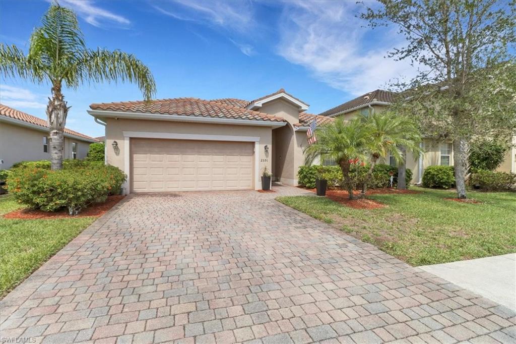 Mediterranean / spanish-style home featuring a tile roof, a front yard, a garage, decorative driveway, and stucco siding