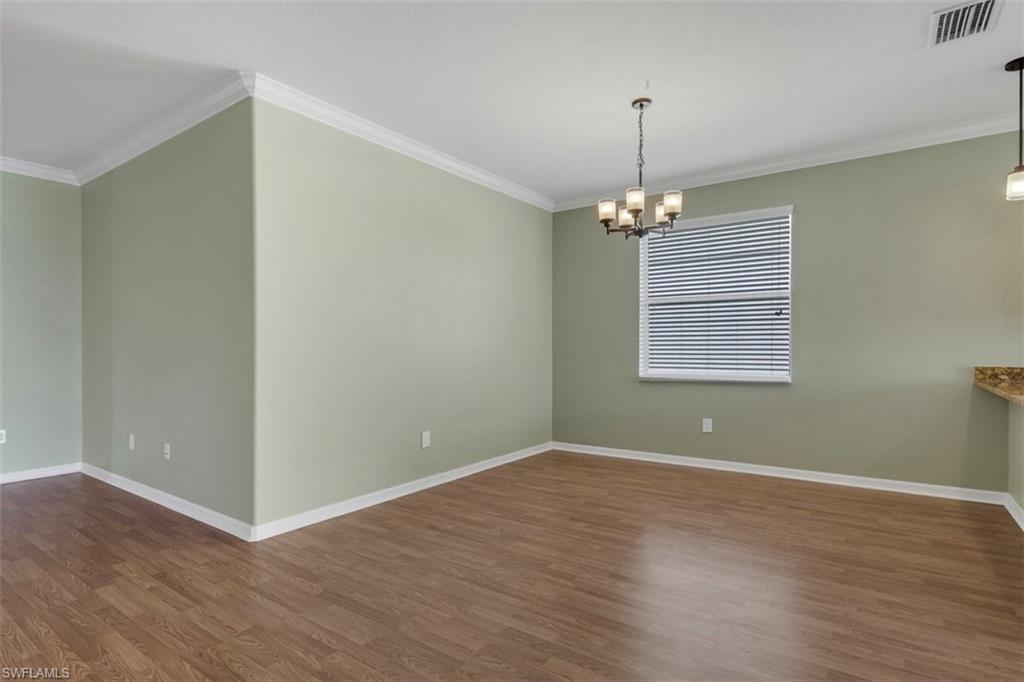 Spare room with ornamental molding, dark wood-style floors, and suspended lighting