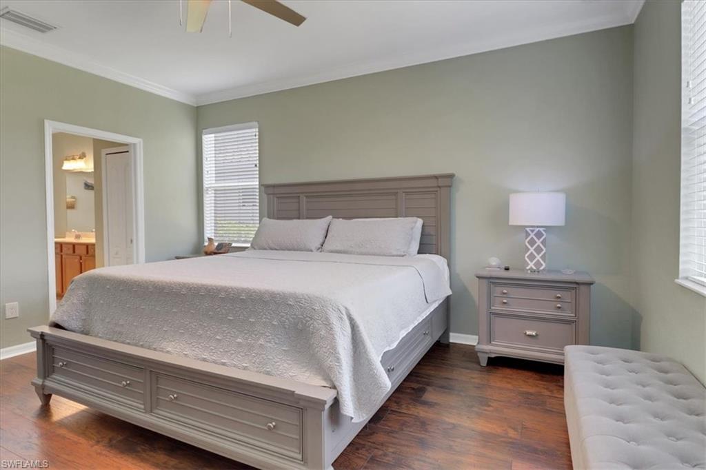 Bedroom featuring dark wood finished floors, baseboards, visible vents, a ceiling fan, and crown molding