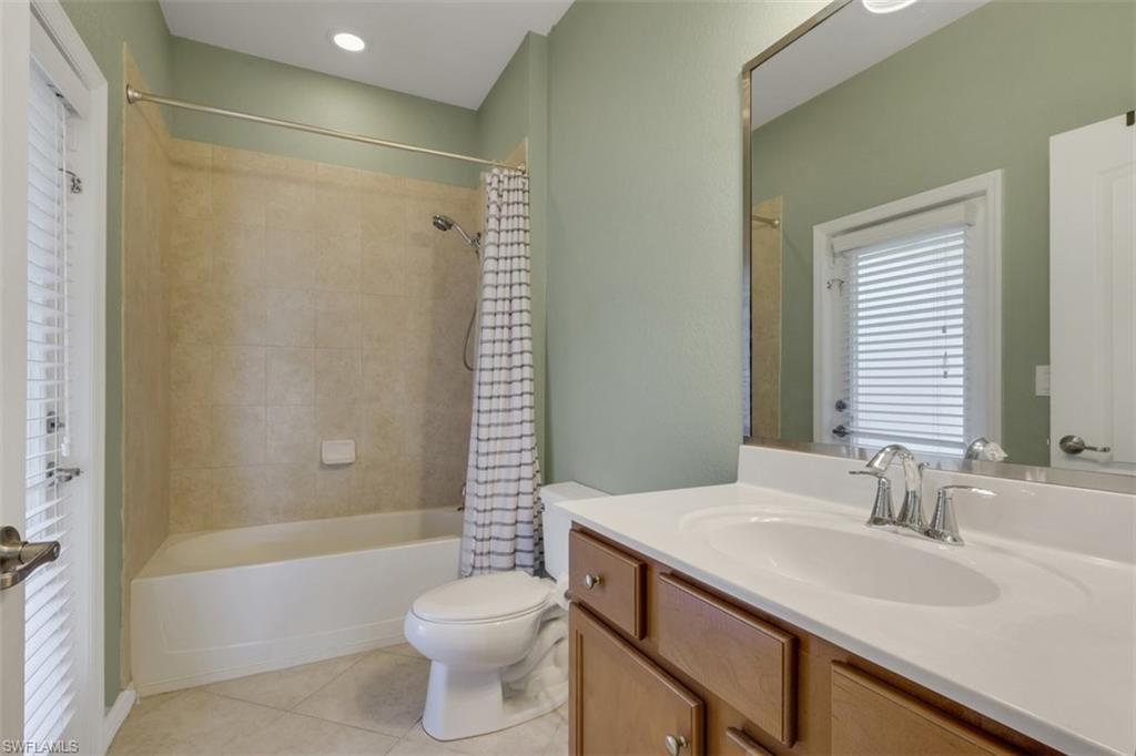 Full bath with vanity, light tile patterned floors, and shower / bath combo with shower curtain