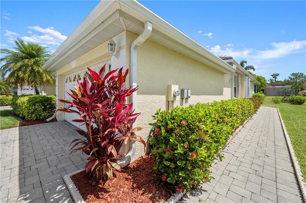 Exterior featuring stucco siding, a white garage door with decorative windows, and a paver driveway