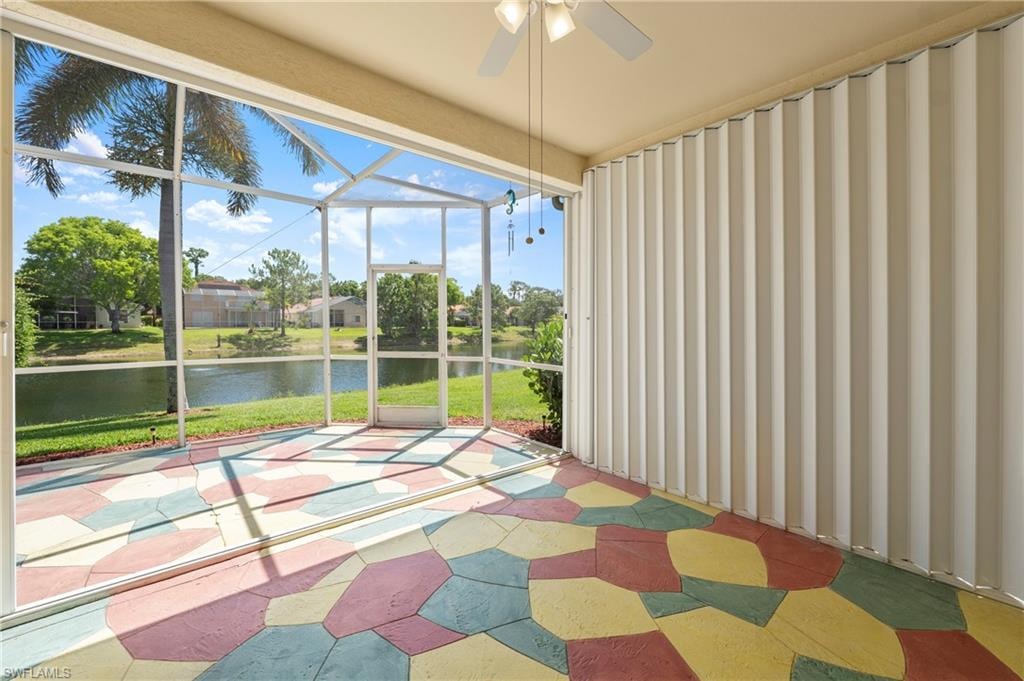 Screened lanai featuring a colorful geometric-patterned floor, ceiling fan, and accordion hurricane shutters