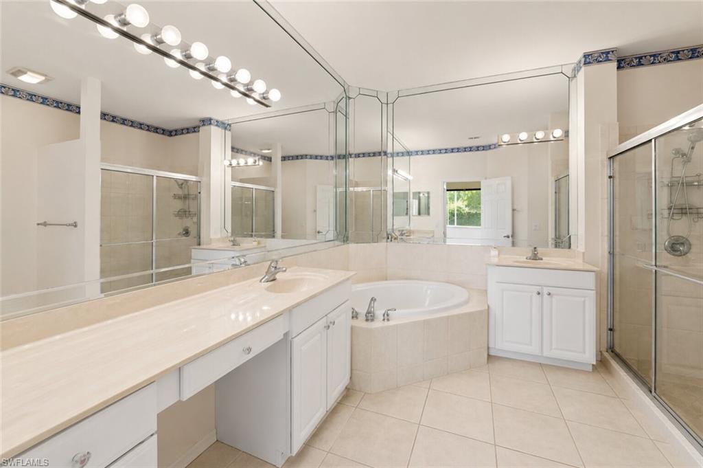 Bathroom featuring a corner soaking tub, two separate vanities with integrated sinks, and a glass-enclosed shower