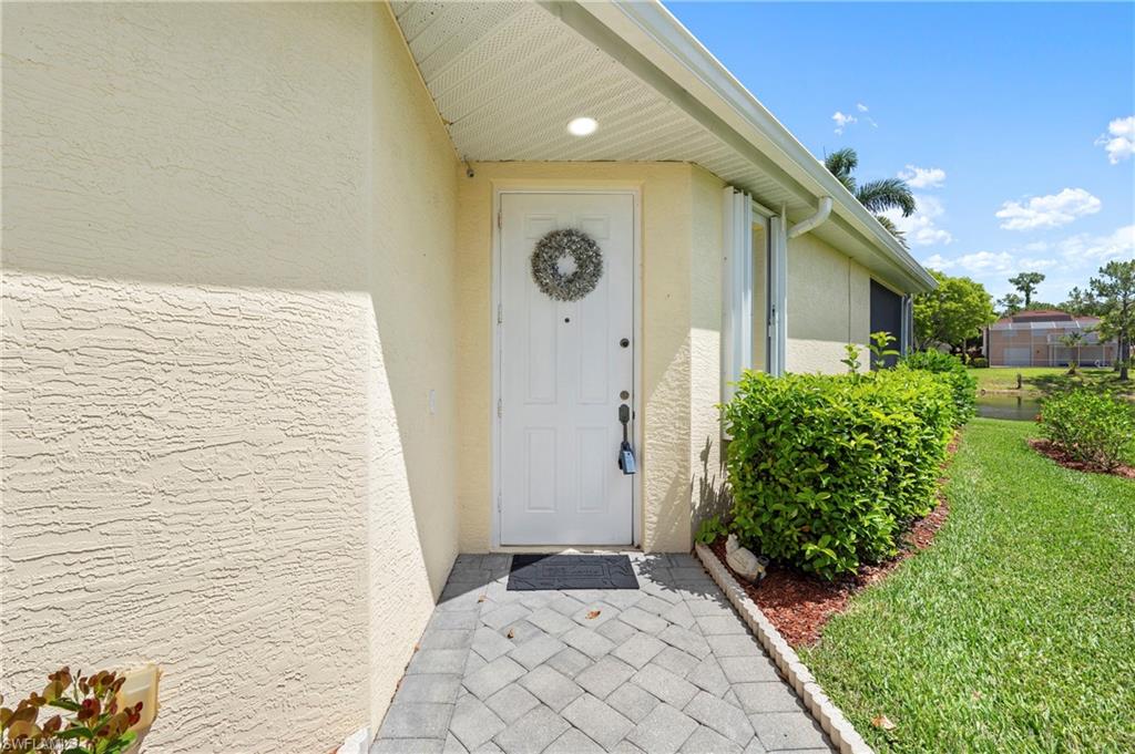 Entryway featuring a paver walkway, stucco exterior, recessed lighting, and manicured landscaping