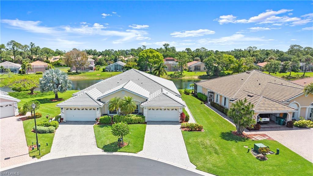 Lakeside property featuring a tile roof, paver driveway, and an attached two-car garage