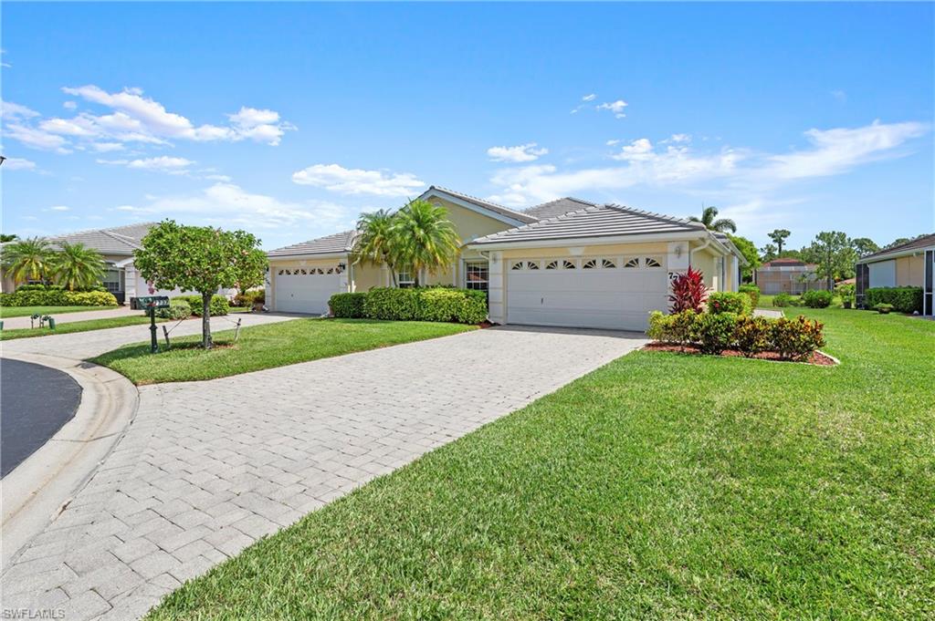 Exterior featuring a concrete tile roof, two-car garage, paver driveway, and mature landscaping