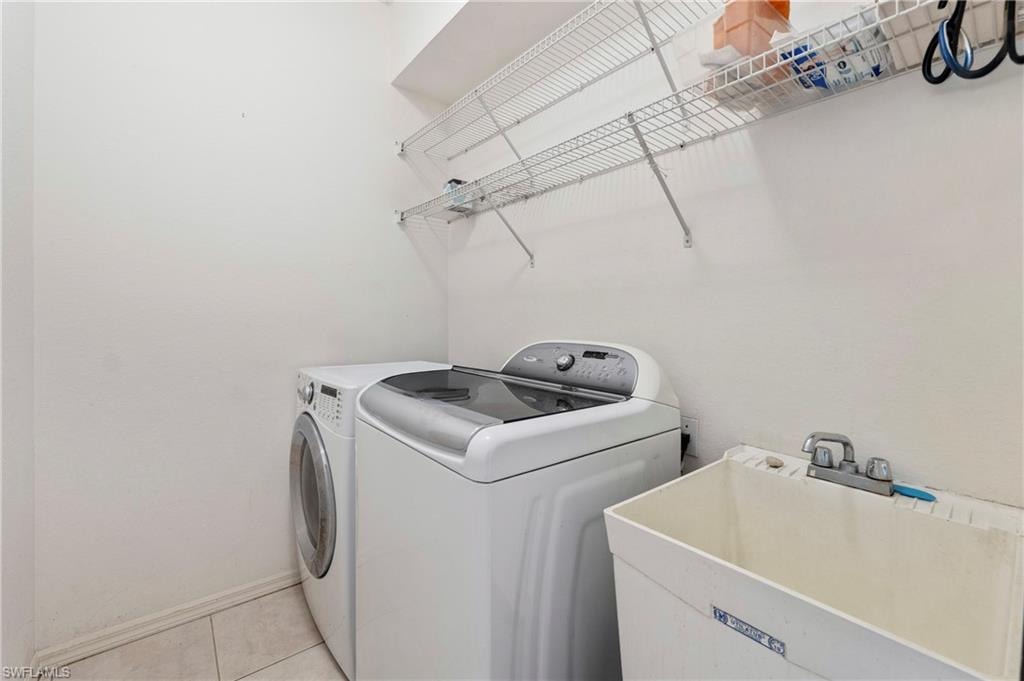 Dedicated laundry space featuring a utility sink, wall-mounted wire shelving, and tile flooring