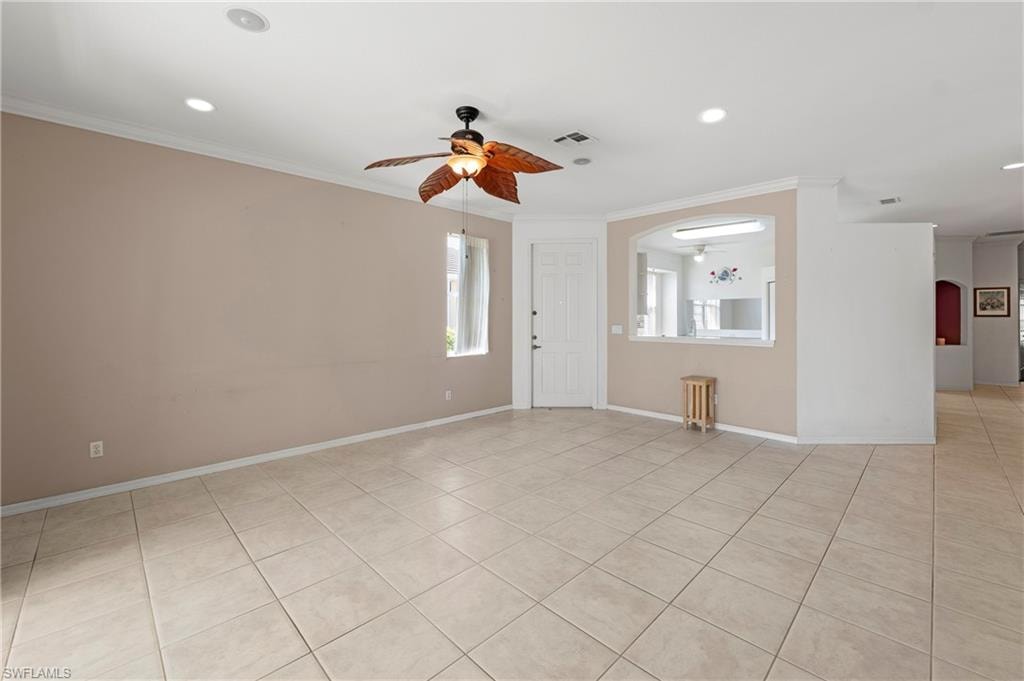 Spacious living area featuring neutral tile flooring, recessed lighting, and a ceiling fan