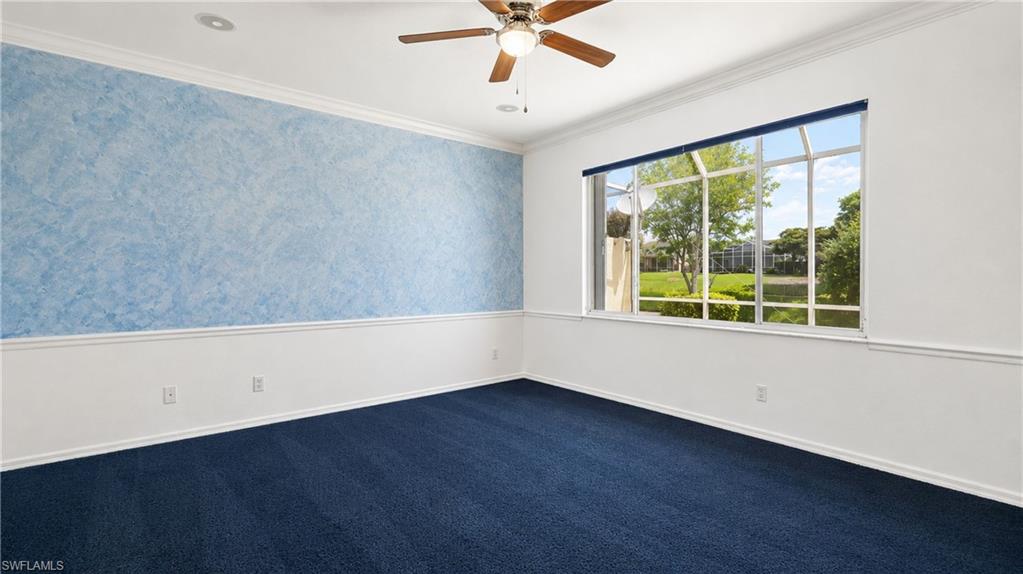 Room featuring a broad window with a green outdoor scenery, ceiling fan, crown molding, and two-tone wall treatment with a blue accent