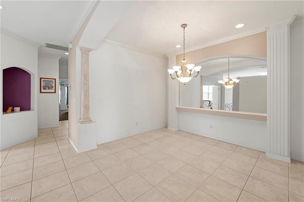 Open living area featuring neutral tile flooring, decorative architectural columns, and a built-in arched niche