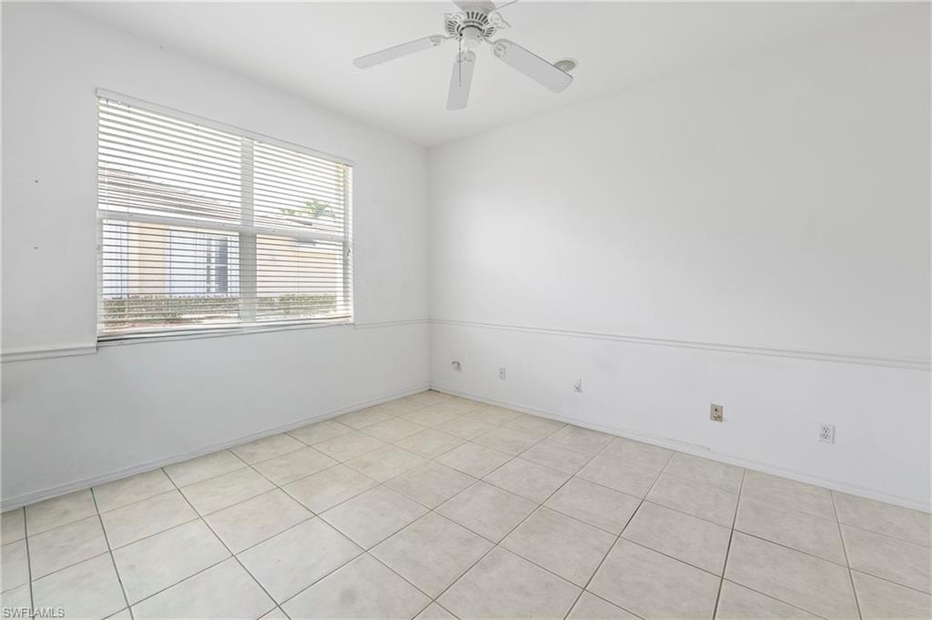 Room featuring light-toned square tile flooring, a window with horizontal blinds, and a white ceiling fan