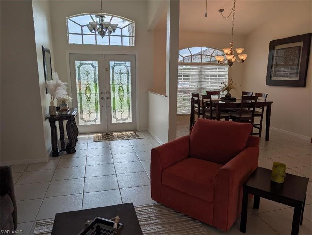 Entrance foyer with a chandelier, baseboards, french doors, tile patterned floors, and a towering ceiling