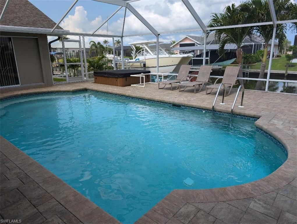 Outdoor pool featuring a hot tub, a patio area, and glass enclosure